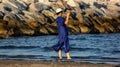 Girl at the eastern beach with long blue dress with feet in the water looking at the relaxed sea, photo taken at Sottomarina Chiog