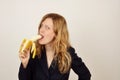 Sensual blonde girl eating banana in black office suit Royalty Free Stock Photo