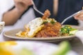 Vietnamese girl eating Com tam - a Vietnamese broken rice with pickles steak grilled pork ribs cucumber onion oil sweet chilies Royalty Free Stock Photo