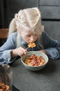 Girl eating corn flakes with milk to the breakfast while sitting at the kitchen Royalty Free Stock Photo