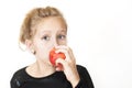 A girl eating delicious red peach with pleasure on a white background. She really loves fruit, more than meat products Royalty Free Stock Photo