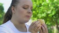 Girl eating fatty high calorie burger, fast food addiction, lack of willpower