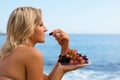 Girl eating grapes at the beach by the sea. Royalty Free Stock Photo