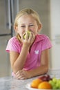 Girl Eating Green Apple At Kitchen Counter Royalty Free Stock Photo