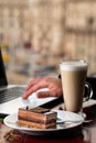 Girl eating piece of cake and cup of latte coffee in a cafe on the blur background of city Royalty Free Stock Photo