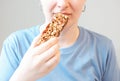 Girl eating protein bar on a gray background close-up. Royalty Free Stock Photo