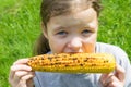 Girl eating a roasted corn cob, closeup view Royalty Free Stock Photo