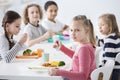 Girl eating vegetables with friends in the canteen during break