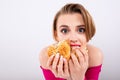 Girl eats with appetite, overweight from fast food, hamburger and french fries in hands, beautiful young girl with bright