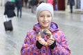 The girl eats a bagel with poppy on a city street, cold day. Royalty Free Stock Photo