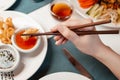 Girl eats Chinese food from a plate with chopsticks. Close-up of hands and food.