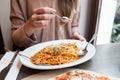 Girl eats Italian pasta with tomato, meat. Close-up spaghetti Bolognese wind it around a fork with a spoon. Parmesan Royalty Free Stock Photo