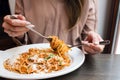 Girl eats Italian pasta with tomato, meat. Close-up spaghetti Bolognese wind it around a fork with a spoon. Parmesan Royalty Free Stock Photo