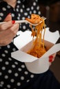 Girl eats pasta with shrimp from a white box with a white fork. Close-up Royalty Free Stock Photo