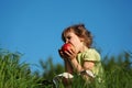 Girl eats red apple in grass against blue sky Royalty Free Stock Photo