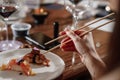 Girl eats sushi with Chinese chopsticks at a table in a restaurant. Close-up of hands. natural light Royalty Free Stock Photo