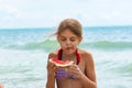 A girl eats a watermelon on the beach