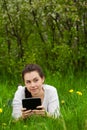 Girl with ebook lying on the grass