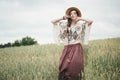 Girl in eco style clothes posing in nature background. Portrait of young woman in boho hat. Pretty ethno stranger in field Royalty Free Stock Photo