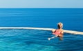 Girl at edge of infinity swimming pool with sea view Royalty Free Stock Photo