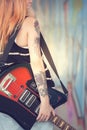 Girl with electric guitar near graffiti wall. Close-up.