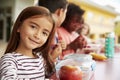 Girl at elementary school lunch table smiling to camera