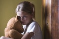 Girl embracing teddy bear in home