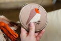 Girl embroiders a bird with a stitch. DIY concept, Hobbies, creativity, clothing and interior decoration