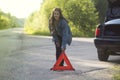 A girl with an emergency sign stands near a car that was involved in an accident