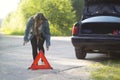 A girl with an emergency sign stands near a car that was involved in an accident