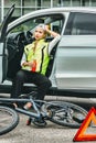 Girl in emergency vest in the car drinks beer. the bike lies on the asphalt Royalty Free Stock Photo