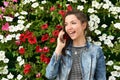 Girl emotionally talking on the phone, against the background of flowers