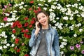 Girl emotionally talking on the phone, against the background of flowers