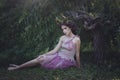 Girl enchanted Princess with horns sitting under a tree. Girl Mystical creature fawn in shabby clothes in a fairy forest