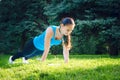 Girl is engaged in fitness in the park, doing exercises. Training on the street in the summer morning. Concept sport healthy Royalty Free Stock Photo