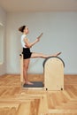 A girl is engaged in Pilates on the reformer reading a book, Pilates classes on the reformer, strengthening the Royalty Free Stock Photo