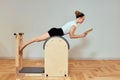 A girl is engaged in Pilates on the reformer reading a book, Pilates classes on the reformer, strengthening the Royalty Free Stock Photo