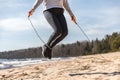 The girl is engaged in sports in nature. exercise with rope, sand and lake. Royalty Free Stock Photo