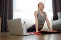 The girl is engaged in stretching at home in front of a laptop. Exercise on stretching the lower back and back