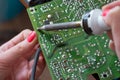 The girl-engineer repairs a switching impulse power supply. Installation and soldering of electronic components. Royalty Free Stock Photo