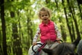 Girl enjoying horseback riding in the woods, young pretty girl with blond curly hair on a horse with backlit leaves Royalty Free Stock Photo