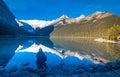 Girl enjoying the reflection of snowy mountain and evergreen tree in the water of lake Louise