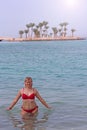 Girl enjoying rest in ocean. Woman relaxing in sea near island with palms trees