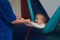 Girl enjoying a sensory therapy on a hammock while physiotherapist assisting her Royalty Free Stock Photo