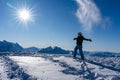 Girl enjoying sunbeams in winter while throwing snow in the air at top of the mountain range Royalty Free Stock Photo