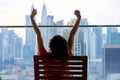 A girl enjoys a scenery view of the modern city center sitting on the balcony of a skyscraper Royalty Free Stock Photo