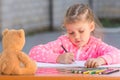 Girl with enthusiasm draws with crayons in the album