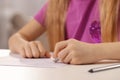 Girl erasing mistake in her homework at white desk indoors