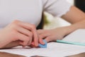 Girl erasing mistake in her notebook at wooden desk, closeup