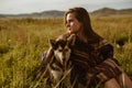 a girl in an ethno cape sits on the steppe grass hugging the dog& x27;s hand Royalty Free Stock Photo